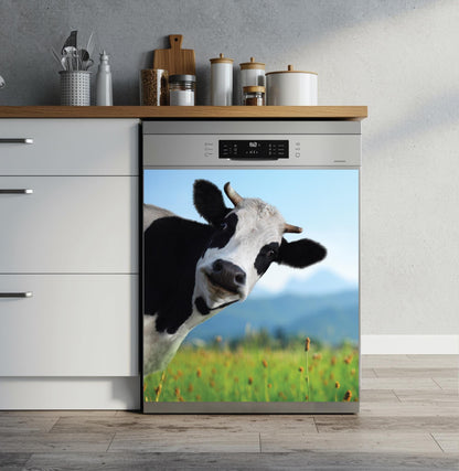 A built-in dishwasher in a modern kitchen setting, featuring a dishwasher magnet print of a black and white cow in a green field under a blue sky on its door.
