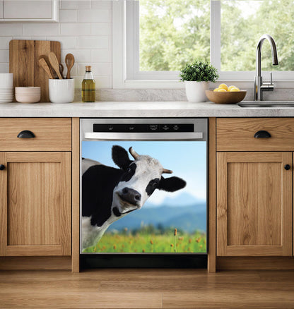 A built-in dishwasher in a modern kitchen setting, featuring a dishwasher magnet print of a black and white cow in a green field under a blue sky on its door.