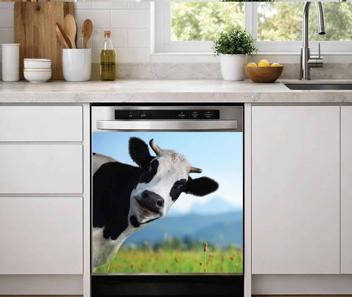 A built-in dishwasher in a modern kitchen setting, featuring a dishwasher magnet print of a black and white cow in a green field under a blue sky on its door.