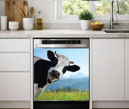 A built-in dishwasher in a modern kitchen setting, featuring a dishwasher magnet print of a black and white cow in a green field under a blue sky on its door.
